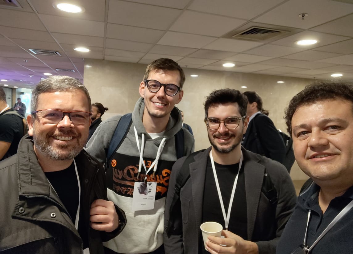 Quatro homens brancos, sendo dois alunos e dois professores, com crachá do evento da IBM  Research Brasil