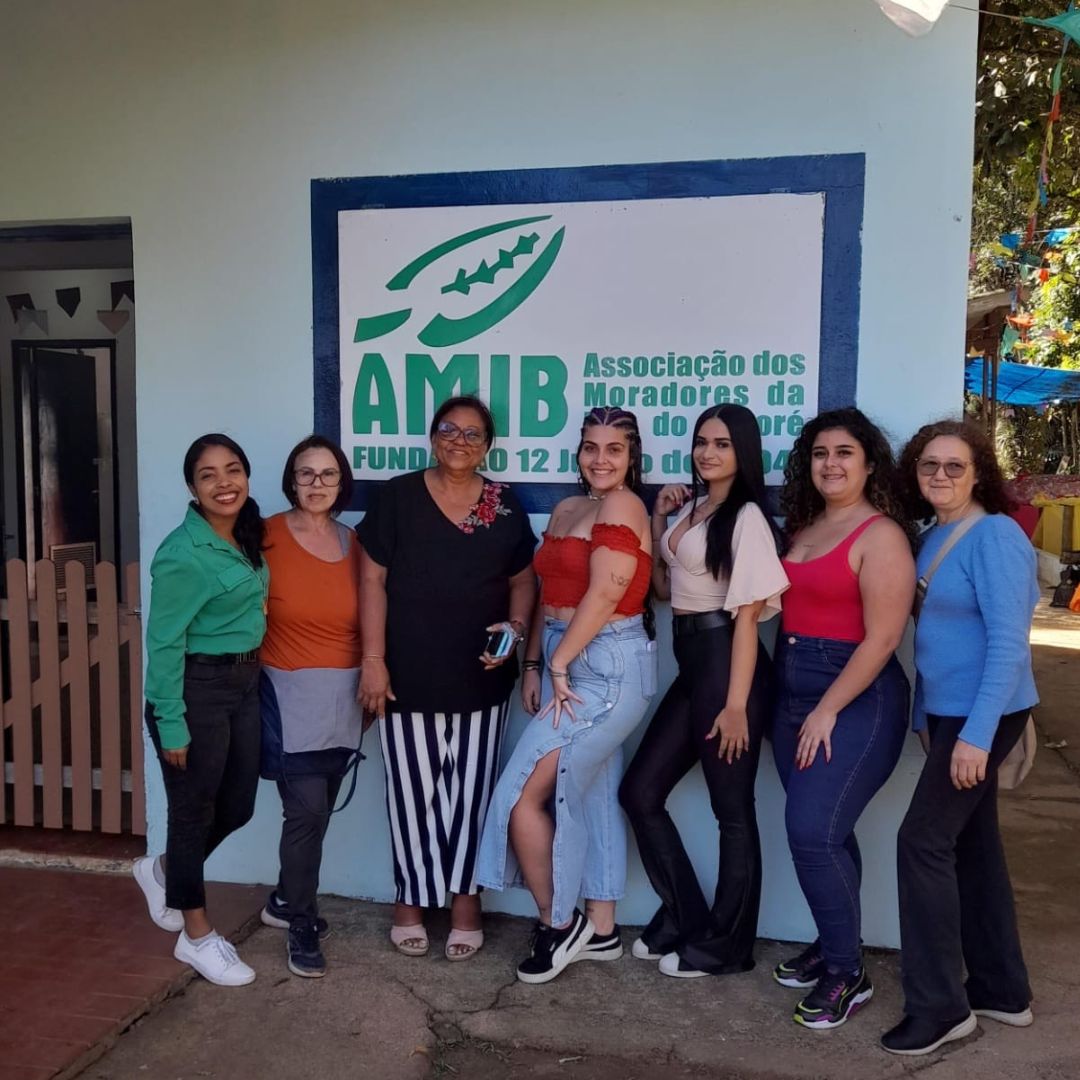 Grupo de  7 mulheres em frente à placa da AMIB